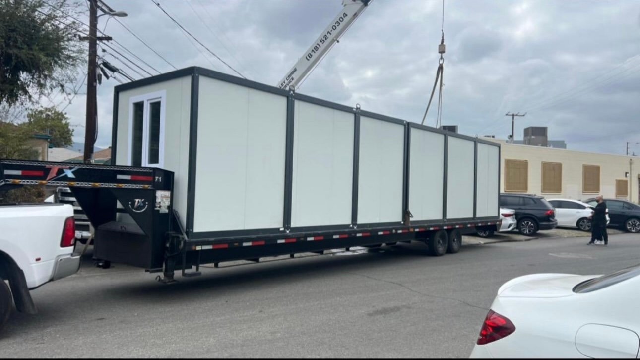 EROUnits office being transported on a trailer under a crane